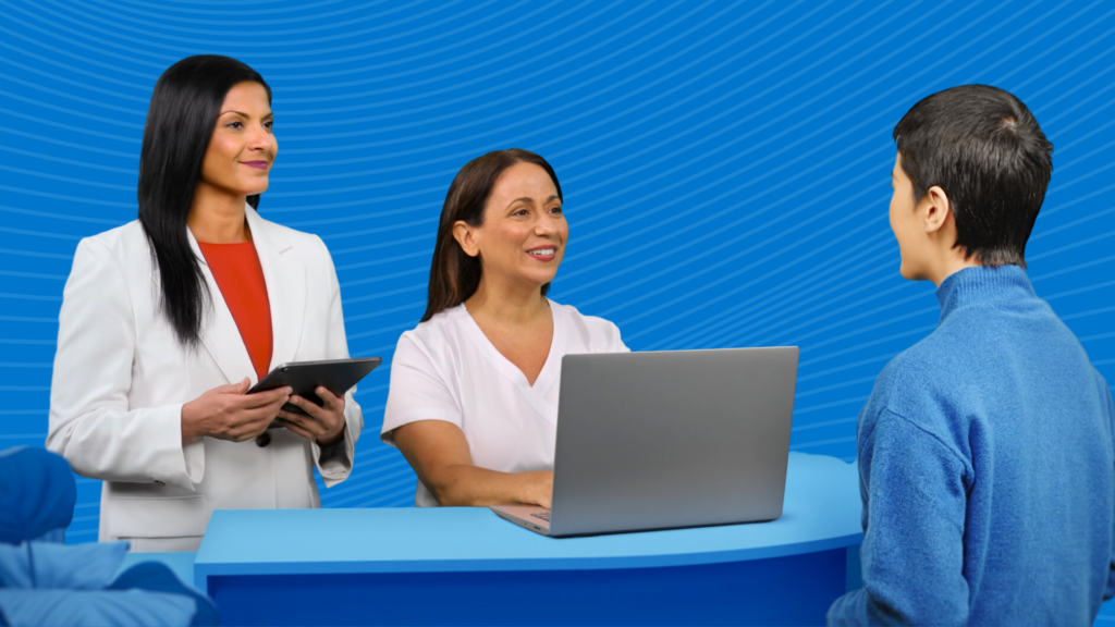 Two healthcare professionals talking to patient from behind a desk with blue background